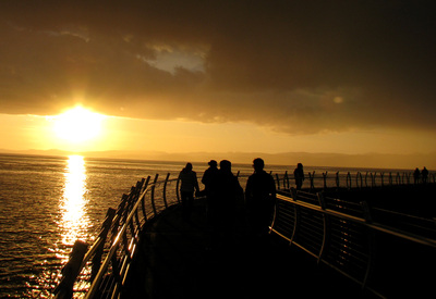 A group of people walking down the Ogden Point Breakwater at sunset in Victoria BC